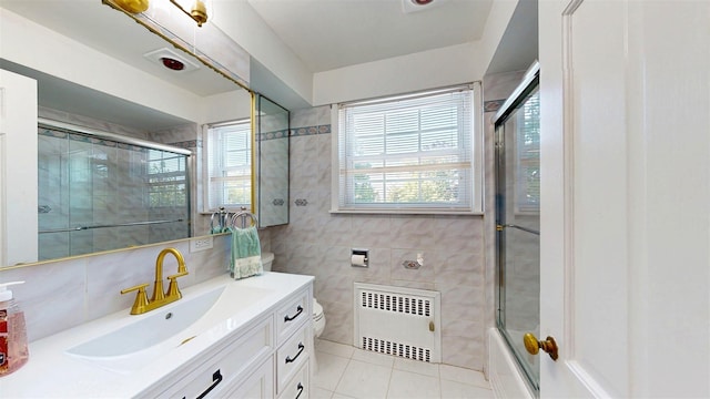 32 Biltmore Ave, Yonkers, NY 10710 - bathroom featuring radiator heating unit, vanity, tile patterned floors, tile walls, and shower / bath combination with glass door