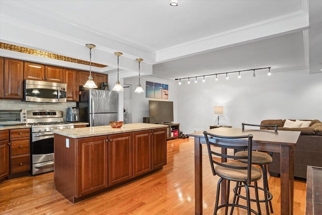 81 Edwards St Unit T, Roslyn Heights, NY 11577 - kitchen featuring appliances with stainless steel finishes, open floor plan, a center island, light wood-style floors, and ornamental molding