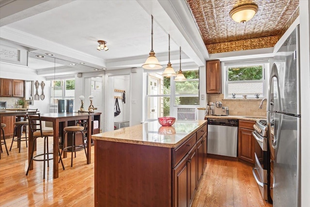 81 Edwards St Unit T, Roslyn Heights, NY 11577 - kitchen featuring appliances with stainless steel finishes, light wood finished floors, backsplash, a center island, and ornamental molding