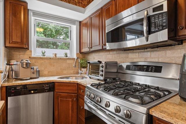 81 Edwards St Unit T, Roslyn Heights, NY 11577 - kitchen featuring appliances with stainless steel finishes, backsplash, brown cabinets, and light stone counters