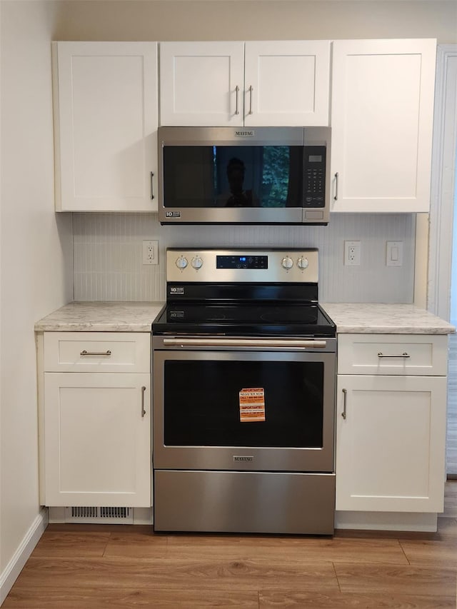 117 Talmadge St, Poughkeepsie, NY 12601 - kitchen featuring appliances with stainless steel finishes, white cabinets, light wood-type flooring, and backsplash