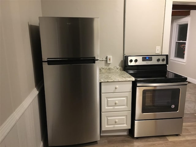 117 Talmadge St, Poughkeepsie, NY 12601 - kitchen featuring appliances with stainless steel finishes, light wood-style flooring, light stone counters, and white cabinets