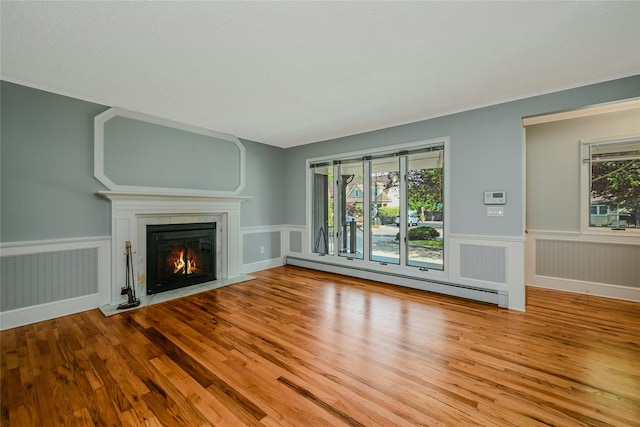 31 Neptune Ave, Mastic, NY 11950 - unfurnished living room featuring a baseboard heating unit, a glass covered fireplace, wainscoting, and wood finished floors
