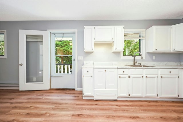 31 Neptune Ave, Mastic, NY 11950 - kitchen featuring white cabinetry, baseboard heating, light wood-style floors, and light stone countertops