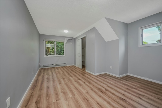 31 Neptune Ave, Mastic, NY 11950 - bonus room featuring a wall mounted AC, a baseboard radiator, light wood-style floors, and healthy amount of natural light