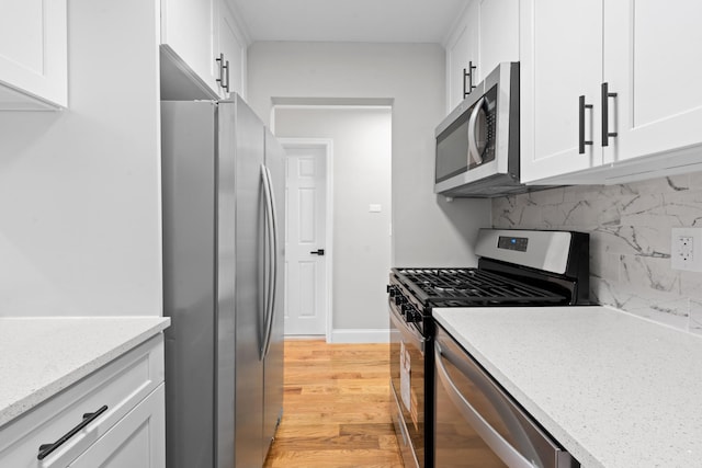 1070 Kelly St, Bronx, NY 10459 - kitchen featuring stainless steel appliances, white cabinets, light wood-style flooring, and decorative backsplash