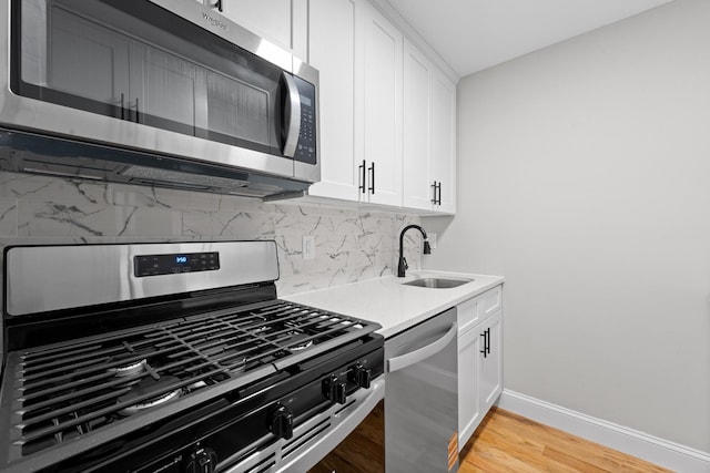 1070 Kelly St, Bronx, NY 10459 - kitchen featuring appliances with stainless steel finishes, backsplash, white cabinetry, light countertops, and light wood finished floors