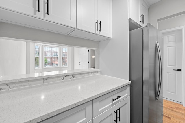 1070 Kelly St, Bronx, NY 10459 - kitchen with freestanding refrigerator, white cabinetry, light stone counters, and light wood-type flooring