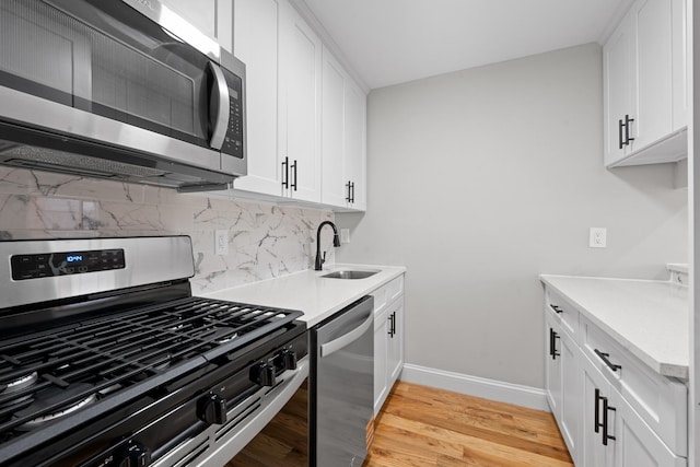 1070 Kelly St, Bronx, NY 10459 - kitchen featuring stainless steel appliances, backsplash, light countertops, light wood-style floors, and white cabinetry
