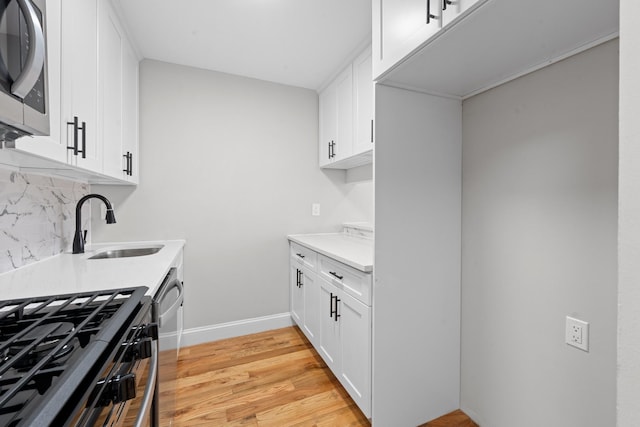1070 Kelly St, Bronx, NY 10459 - kitchen featuring stainless steel appliances, light wood-style flooring, backsplash, light countertops, and white cabinetry