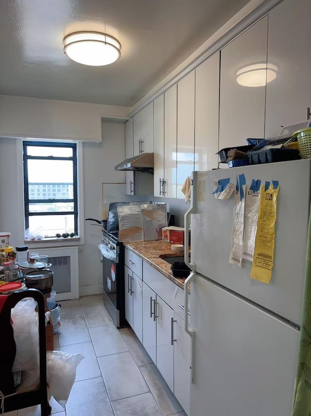 14450 38th Ave Unit B5, Flushing, NY 11354 - kitchen with freestanding refrigerator, under cabinet range hood, range with electric cooktop, light tile patterned floors, and white cabinetry
