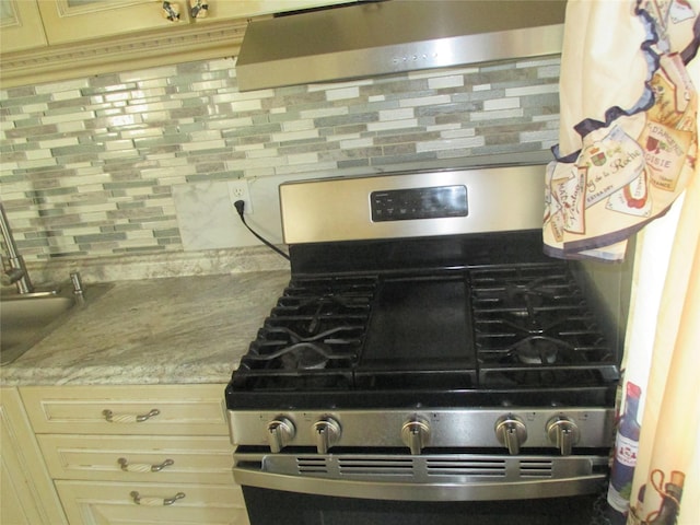 6 2nd Pl, Roosevelt, NY 11575 - kitchen view of stainless steel gas range, tasteful backsplash, light countertops, and range hood