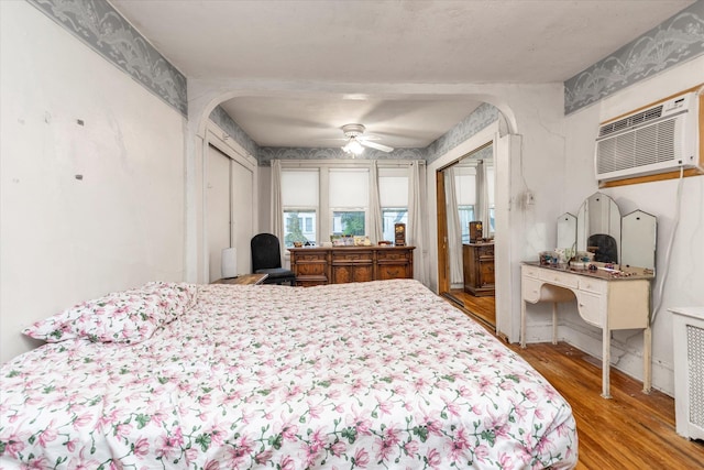 48 Carstairs Rd, Valley Stream, NY 11581 - bedroom with wood finished floors, a wall unit AC, arched walkways, and a ceiling fan