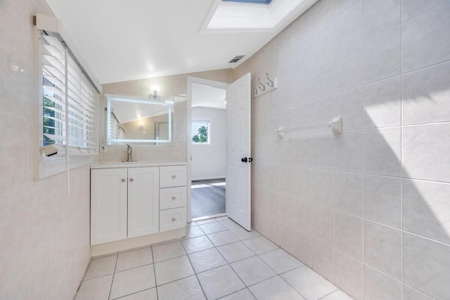32 Clarkson Rd, Centereach, NY 11720 - bathroom featuring vanity, tile walls, lofted ceiling, a skylight, and tile patterned floors