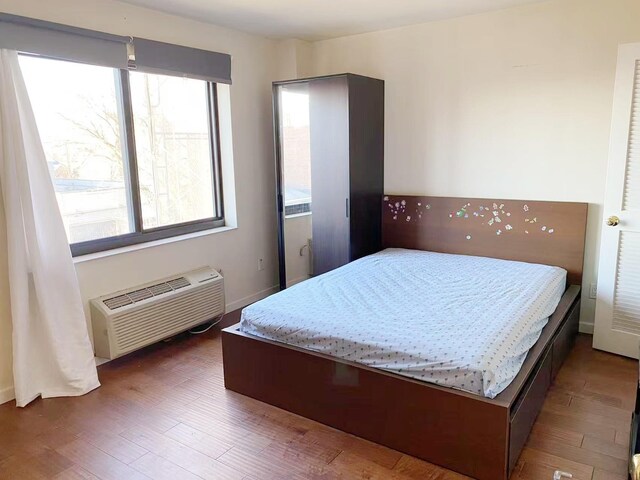 3138 137th St Unit 5A, Flushing, NY 11354 - bedroom featuring a wall mounted air conditioner and wood finished floors