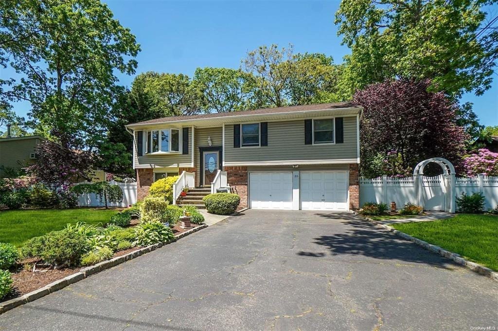 35 40th St, Islip, NY 11751 - split foyer home with asphalt driveway, an attached garage, and brick siding