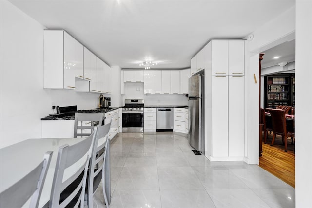 22 Sharon Dr, Spring Valley, NY 10977 - kitchen featuring stainless steel appliances, light tile patterned floors, dark countertops, and white cabinetry