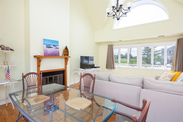 10 Bayview Rd, Remsenburg, NY 11960 - dining area featuring a chandelier, wood finished floors, healthy amount of natural light, a glass covered fireplace, and a high ceiling