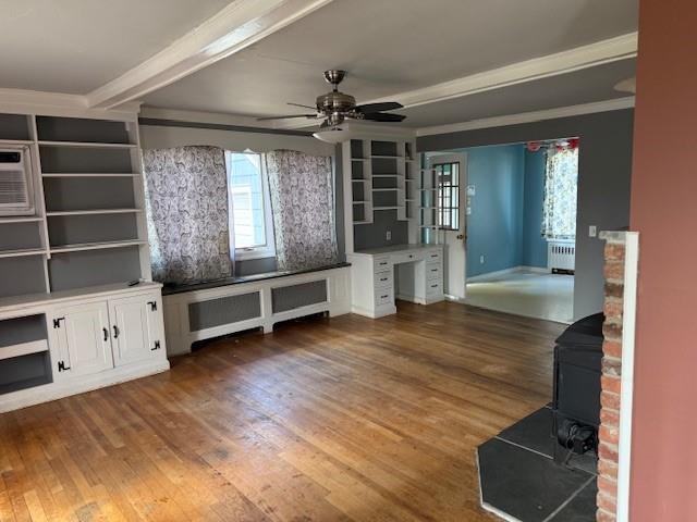 624 Adams Ave, Lindenhurst, NY 11757 - unfurnished living room featuring radiator, a wood stove, wood finished floors, ceiling fan, and ornamental molding