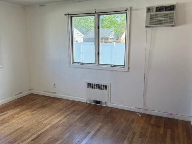 624 Adams Ave, Lindenhurst, NY 11757 - unfurnished room featuring radiator, wood finished floors, and a wall mounted air conditioner