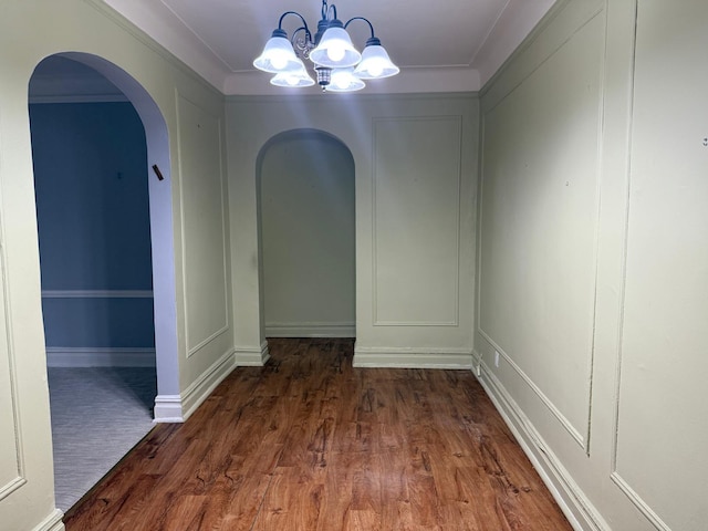 1 Meadow Dr Unit 3D, Woodmere, NY 11598 - unfurnished dining area featuring arched walkways, a chandelier, dark wood finished floors, ornamental molding, and a decorative wall