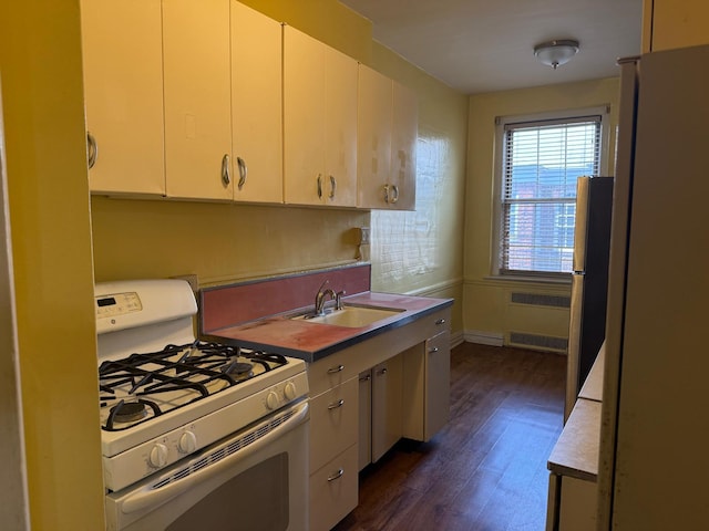 1 Meadow Dr Unit 3D, Woodmere, NY 11598 - kitchen with white gas stove, radiator heating unit, dark wood-style floors, white cabinetry, and freestanding refrigerator