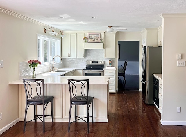 306 S Centerville Rd, Middletown, NY 10940 - kitchen with stainless steel appliances, a peninsula, a breakfast bar, light countertops, and dark wood-style floors