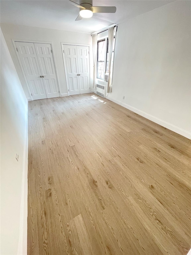 8385 116th St Unit 4B, Kew Gardens, NY 11418 - unfurnished bedroom featuring light wood-style flooring, multiple closets, radiator heating unit, and ceiling fan