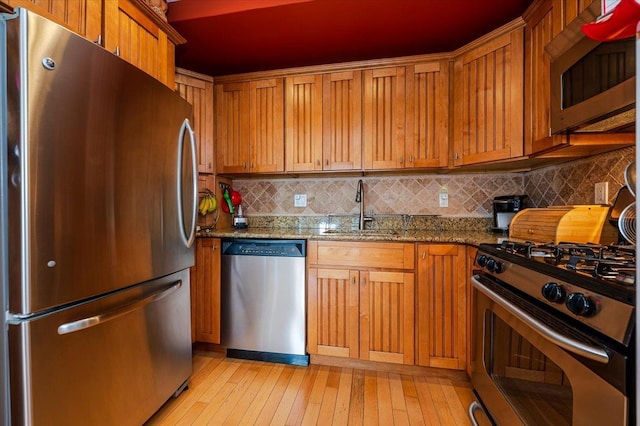 600 Clarence Ave Unit 1J, Bronx, NY 10465 - kitchen featuring appliances with stainless steel finishes, tasteful backsplash, stone counters, light wood finished floors, and brown cabinetry