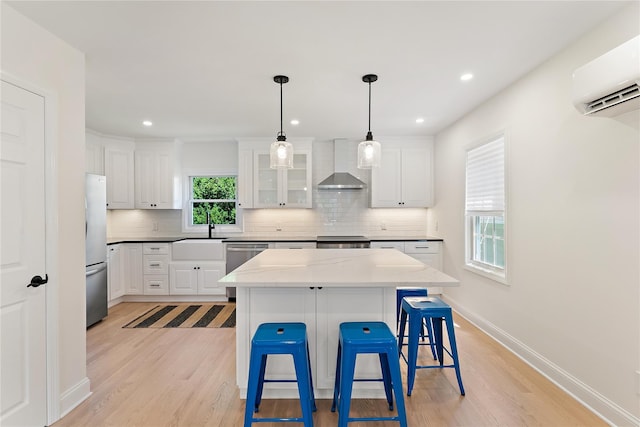 1 Saunders St, Hastings-On-Hudson, NY 10706 - kitchen featuring wall chimney exhaust hood, appliances with stainless steel finishes, backsplash, an AC wall unit, and light wood-style floors
