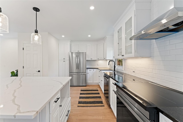 1 Saunders St, Hastings-On-Hudson, NY 10706 - kitchen featuring appliances with stainless steel finishes, wall chimney range hood, light wood-style floors, white cabinets, and decorative backsplash