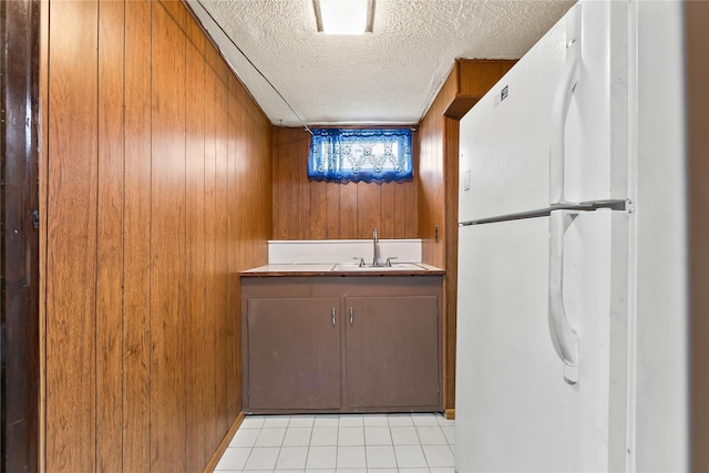 154-70 11th Ave, Beechhurst, NY 11357 - kitchen with freestanding refrigerator, a textured ceiling, wooden walls, light tile patterned floors, and brown cabinets