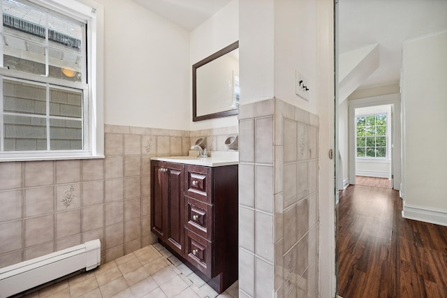 1639 Hone Ave, Bronx, NY 10461 - bathroom featuring a baseboard radiator, vanity, tile walls, a wainscoted wall, and wood finished floors