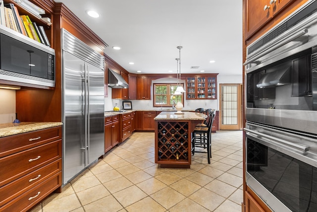 42 E Webster St, Merrick, NY 11566 - kitchen featuring built in appliances, wall chimney exhaust hood, light tile patterned flooring, a kitchen breakfast bar, and recessed lighting