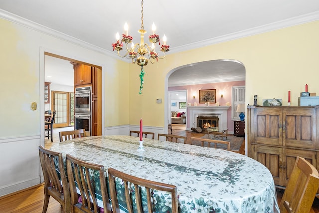 42 E Webster St, Merrick, NY 11566 - dining room with a warm lit fireplace, arched walkways, crown molding, a chandelier, and light wood-style flooring
