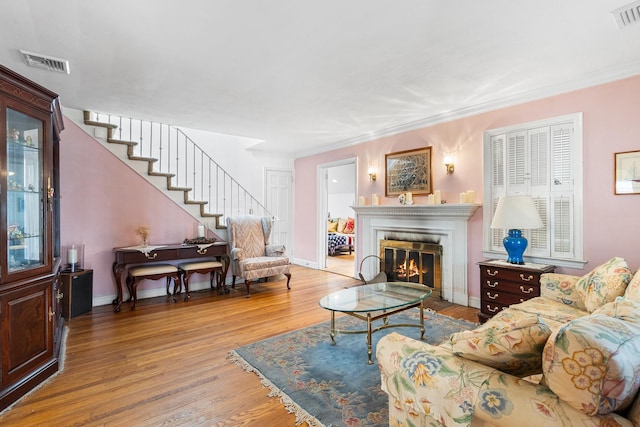42 E Webster St, Merrick, NY 11566 - living area featuring wood finished floors, a fireplace with flush hearth, stairs, and ornamental molding