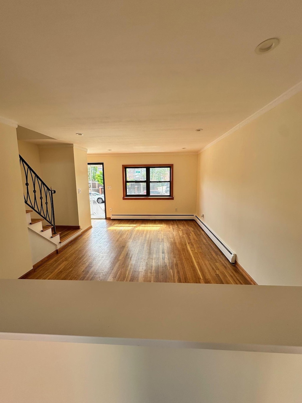 53-26 61st St, Maspeth, NY 11378 - unfurnished living room with a baseboard radiator, ornamental molding, wood finished floors, and stairway