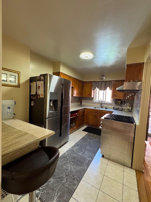 4406 Murdock Ave, Bronx, NY 10466 - kitchen featuring appliances with stainless steel finishes, wall chimney range hood, light countertops, brown cabinetry, and backsplash