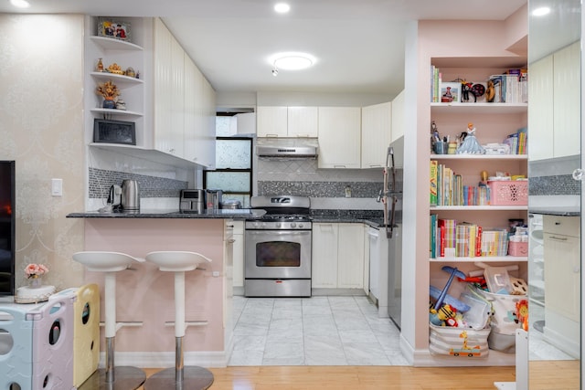 140-10 84th Dr Unit 2B, Briarwood, NY 11435 - kitchen with stainless steel gas range oven, under cabinet range hood, open shelves, and backsplash