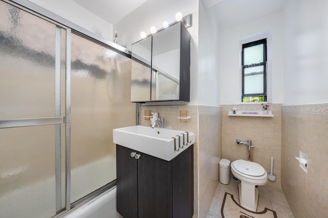 140-10 84th Dr Unit 2B, Briarwood, NY 11435 - bathroom with tile patterned floors, vanity, tile walls, a wainscoted wall, and shower / bath combination with glass door