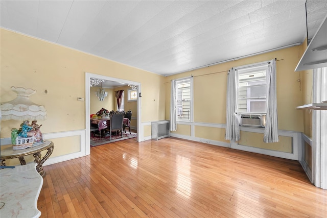 966 E 42nd St, Brooklyn, NY 11210 - unfurnished room featuring radiator, light wood-style flooring, cooling unit, and a wainscoted wall