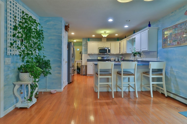 22 Indian Ave, Flanders, NY 11901 - kitchen featuring stainless steel appliances, a peninsula, white cabinetry, light wood-type flooring, and recessed lighting