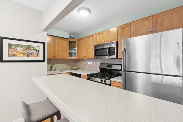 301 E 69th St Unit 4C, New York Manhattan, NY 10021 - kitchen with stainless steel appliances, light countertops, backsplash, glass insert cabinets, and a kitchen breakfast bar