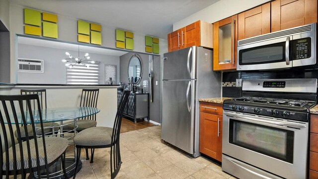 95 Foster Ave, Valley Stream, NY 11580 - kitchen with appliances with stainless steel finishes, brown cabinetry, a chandelier, a wall mounted air conditioner, and glass insert cabinets