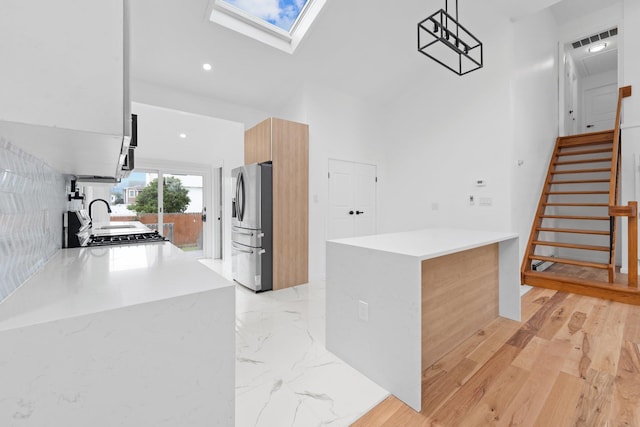 2572 Riverside Ave, Seaford, NY 11783 - kitchen with stainless steel fridge, modern cabinets, a skylight, light countertops, and a high ceiling