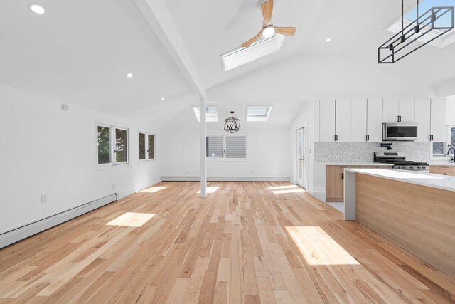 2572 Riverside Ave, Seaford, NY 11783 - unfurnished living room featuring a skylight, light wood-type flooring, baseboard heating, ceiling fan, and high vaulted ceiling