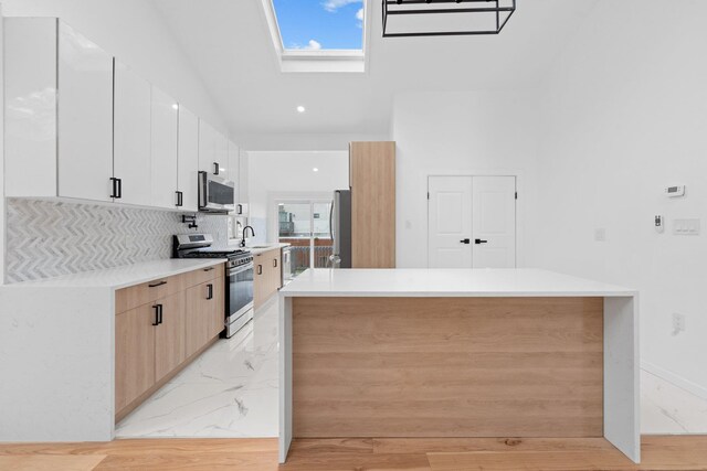 2572 Riverside Ave, Seaford, NY 11783 - kitchen with appliances with stainless steel finishes, a skylight, modern cabinets, light countertops, and tasteful backsplash
