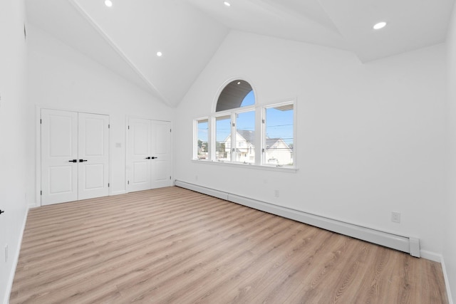 2572 Riverside Ave, Seaford, NY 11783 - unfurnished bedroom featuring baseboard heating, multiple closets, high vaulted ceiling, wood finished floors, and recessed lighting