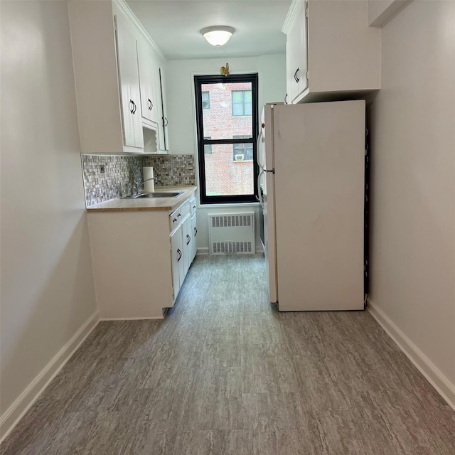 83-20 98th St Unit 1H, Woodhaven, NY 11421 - kitchen featuring freestanding refrigerator, radiator heating unit, wood finished floors, white cabinetry, and backsplash