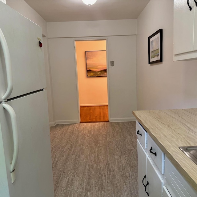 83-20 98th St Unit 1H, Woodhaven, NY 11421 - kitchen with freestanding refrigerator, wood finished floors, light countertops, and white cabinetry